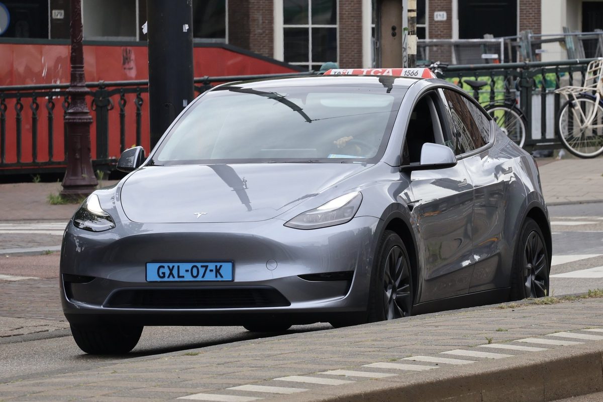 Grey Tesla Model Y on an Amsterdam street with parked bicycles in the background