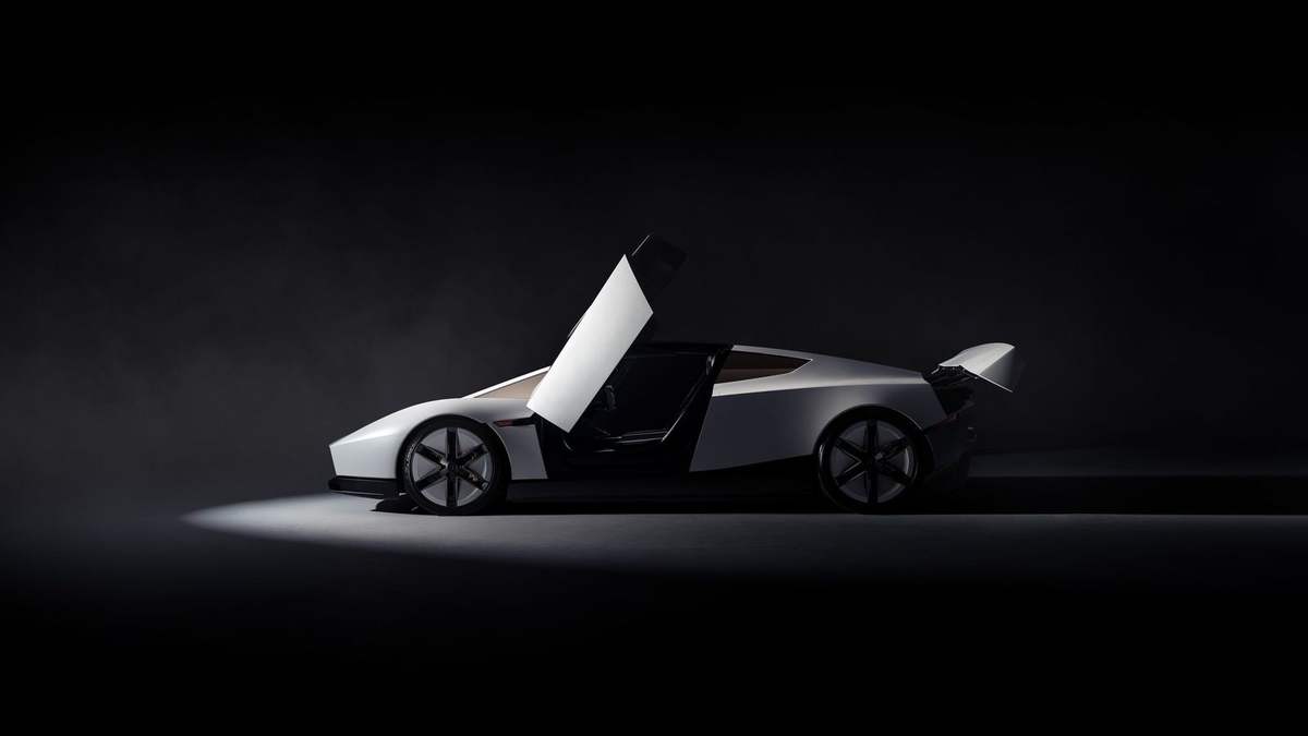 White Tesla Roadster with its doors raised, seen from the side in a dark studio